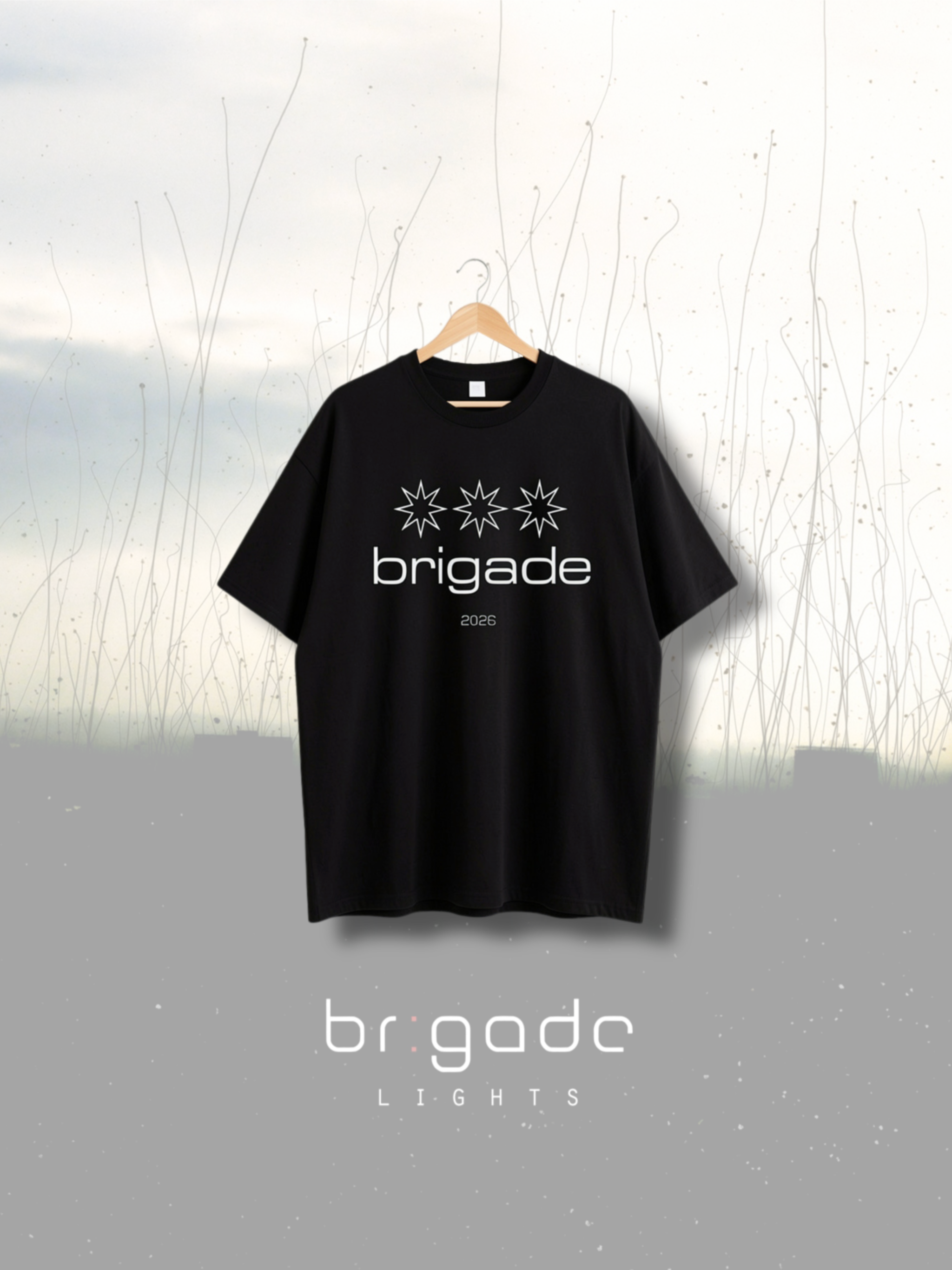 Black t-shirt with 'brigade' logo on a hanger against a natural background